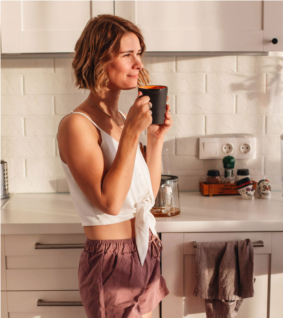 a woman in her kitchen drinking coffee